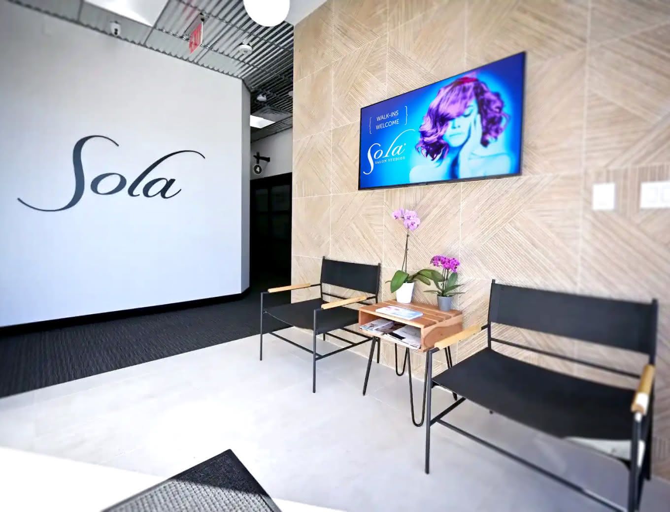 Sola Salon Studios lobby with TV and digital signage displaying branded content