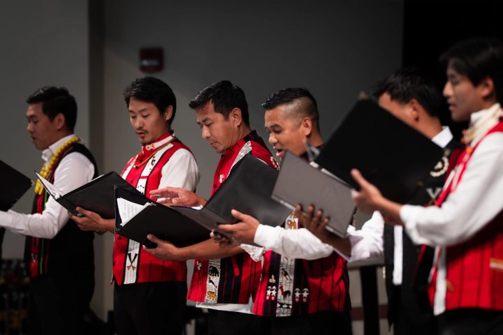 Photograph of musicians singing from printed music sheets at the First Naga Baptist Fundraising Cultural Event.
