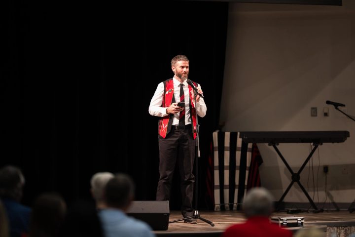 Photograph of a speaker in traditional attire addressing the audience at the First Naga Baptist Fundraising Cultural Event.