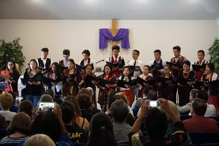 Church choir singing before the congregation beneath a draped cross