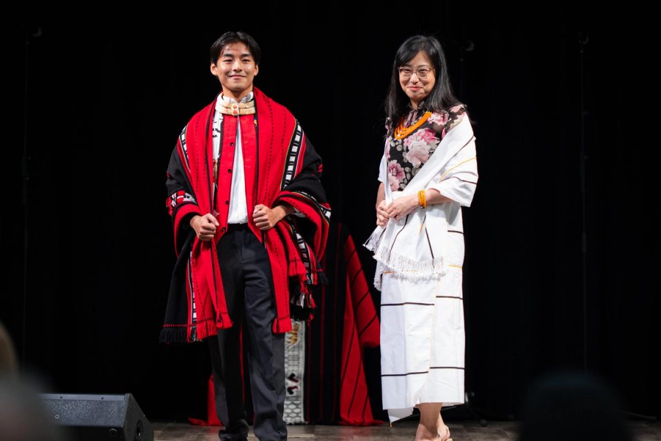 Photograph of two performers standing together on stage at the First Naga Baptist Fundraising Cultural Event.