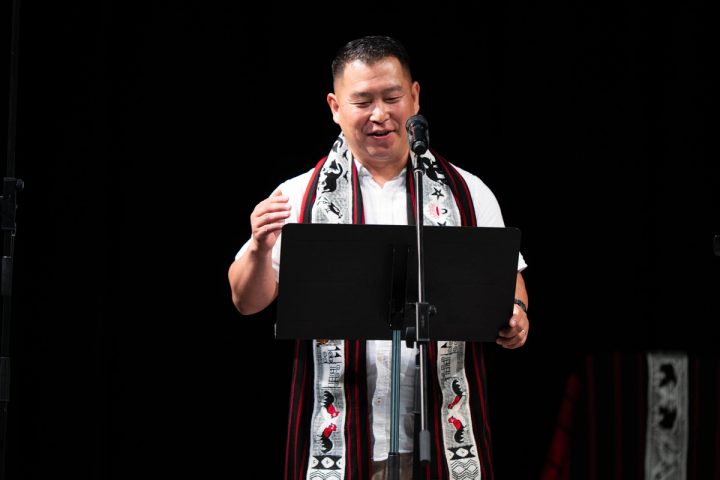 Photograph of a speaker reading from a lectern at the First Naga Baptist Fundraising Cultural Event.