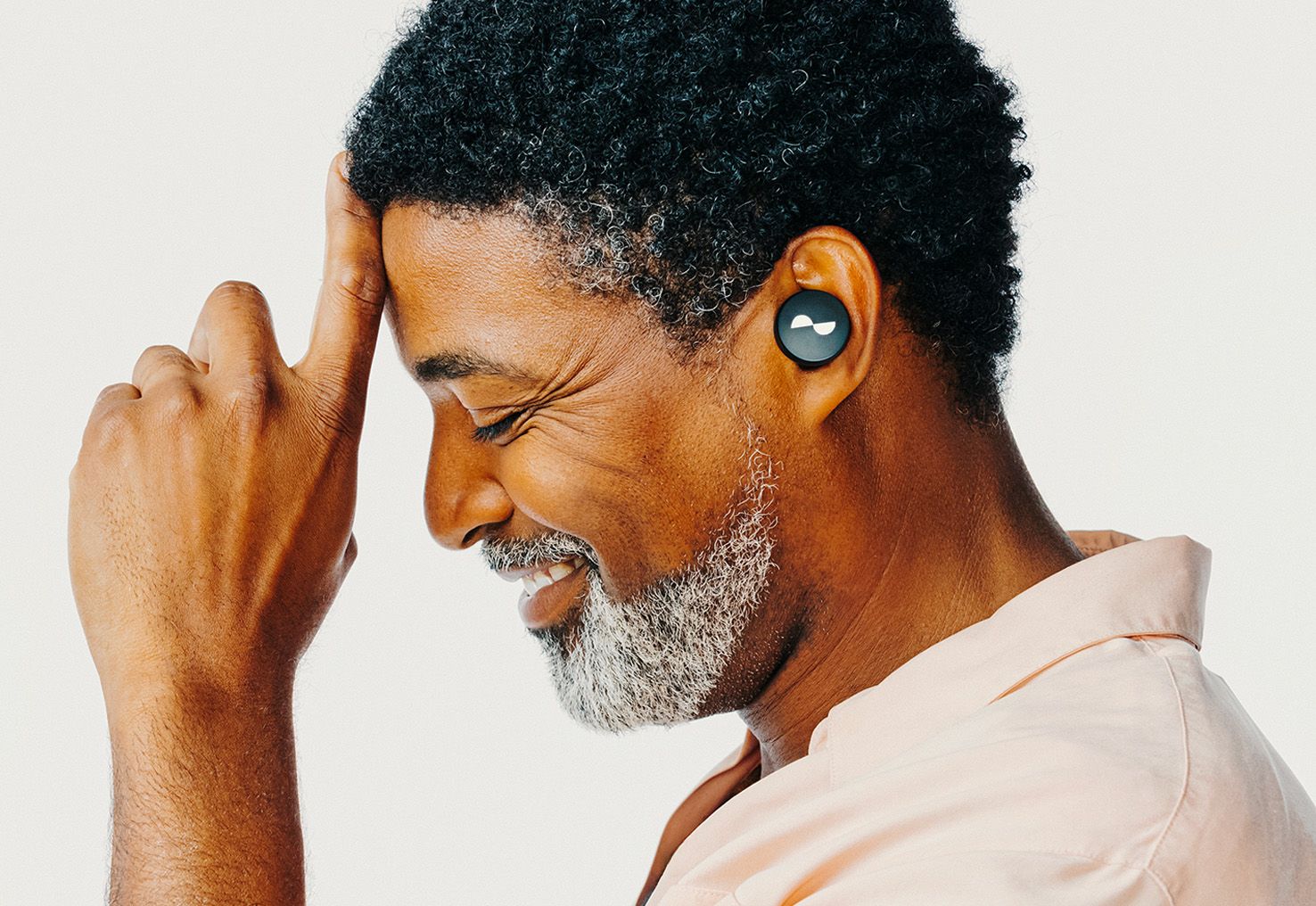 Person with eyes closed listening to sound with NURATRUE earbuds in ears