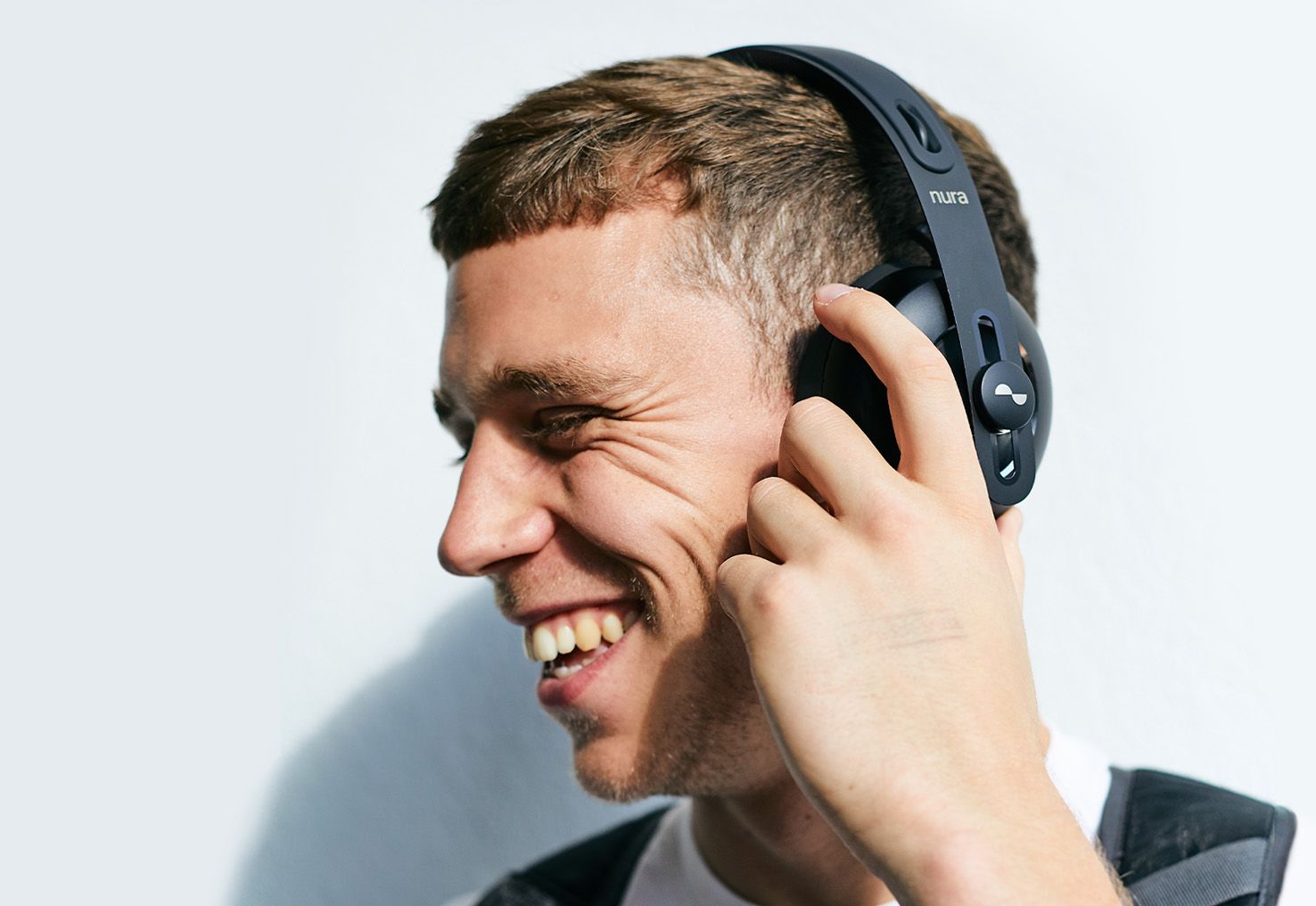 Person laughing with their NURAPHONE headphones on ears whilst enabling active noise cancellation