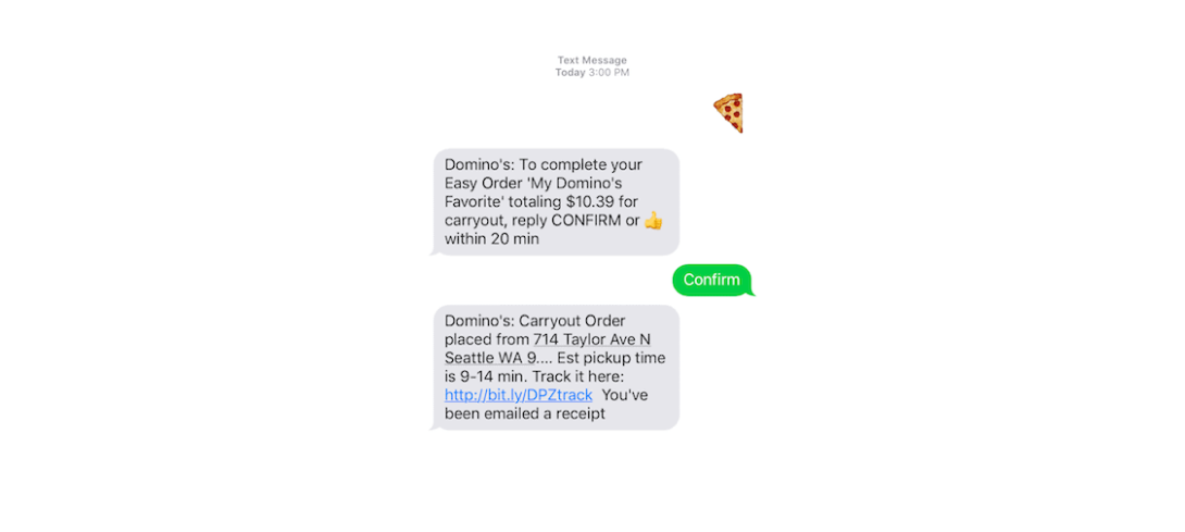 A text thread: the customer sends a single pizza-slice emoji; Domino’s replies “To complete your Easy Order ‘My Domino’s Favorite’ totaling $10.39 for carryout, reply CONFIRM or a thumbs-up within 20 min”; the customer replies “Confirm”; Domino’s confirms the carryout order from 714 Taylor Ave N, Seattle, with a 9–14 minute pickup estimate and a tracking link