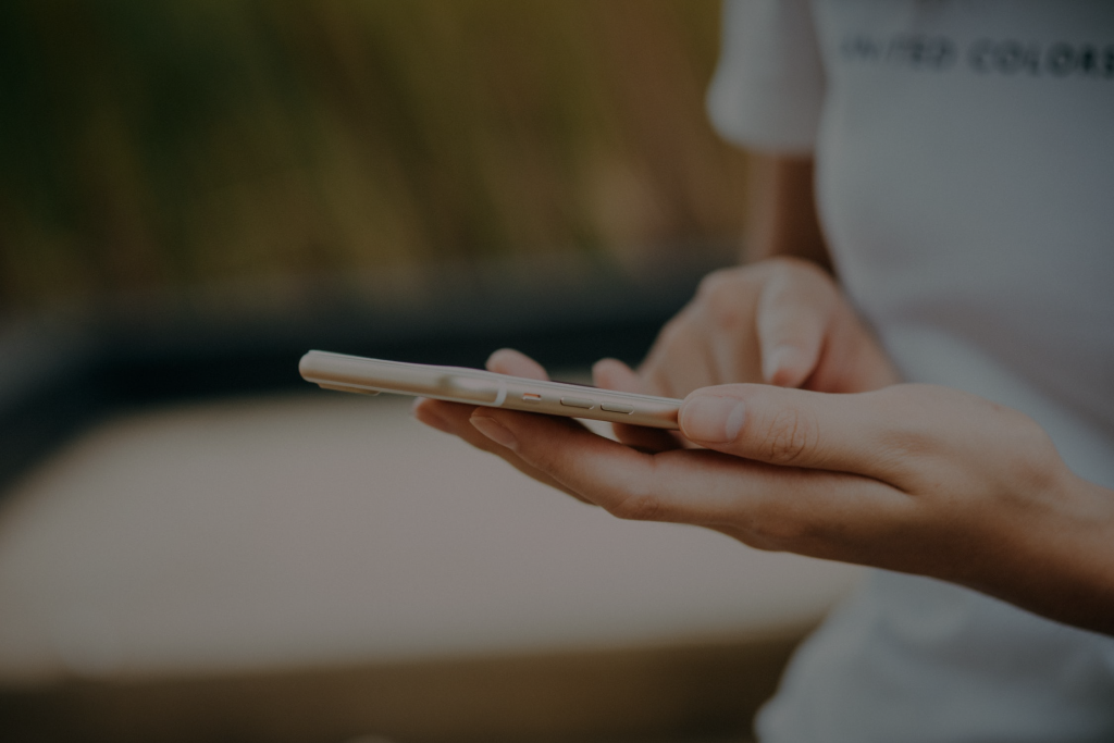 Close-up of a person holding a smartphone in both hands, thumbs resting over the screen