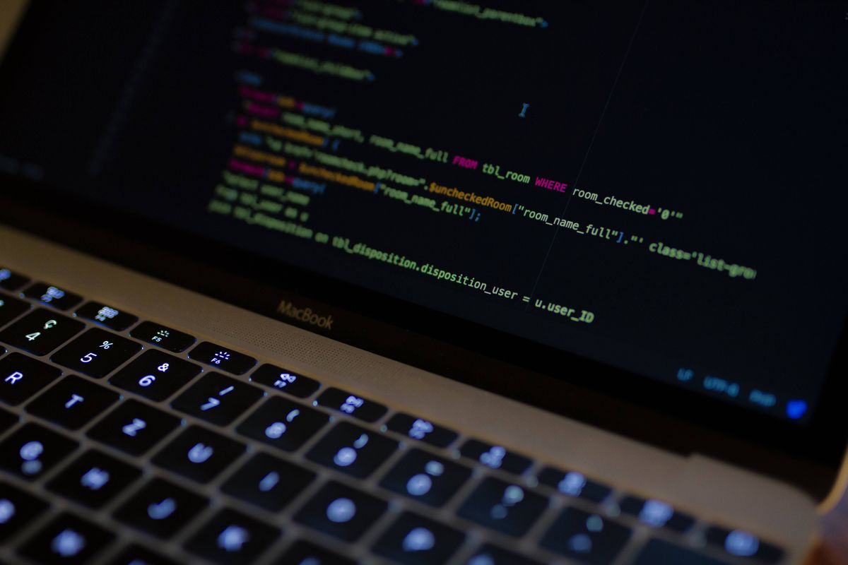 Source code in a dark editor on a laptop screen with a backlit keyboard