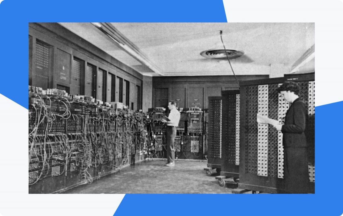 Archive photograph of the ENIAC room, two operators setting switches on wall-sized racks of early computing hardware