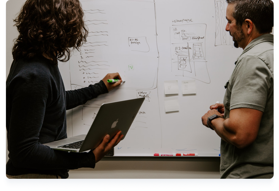 Two colleagues brainstorming on a whiteboard