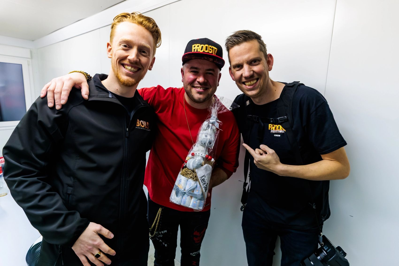 Drie lachende crewleden van Bold Productions poseren samen in een lichte backstageruimte, gemaakt door Bold Productions