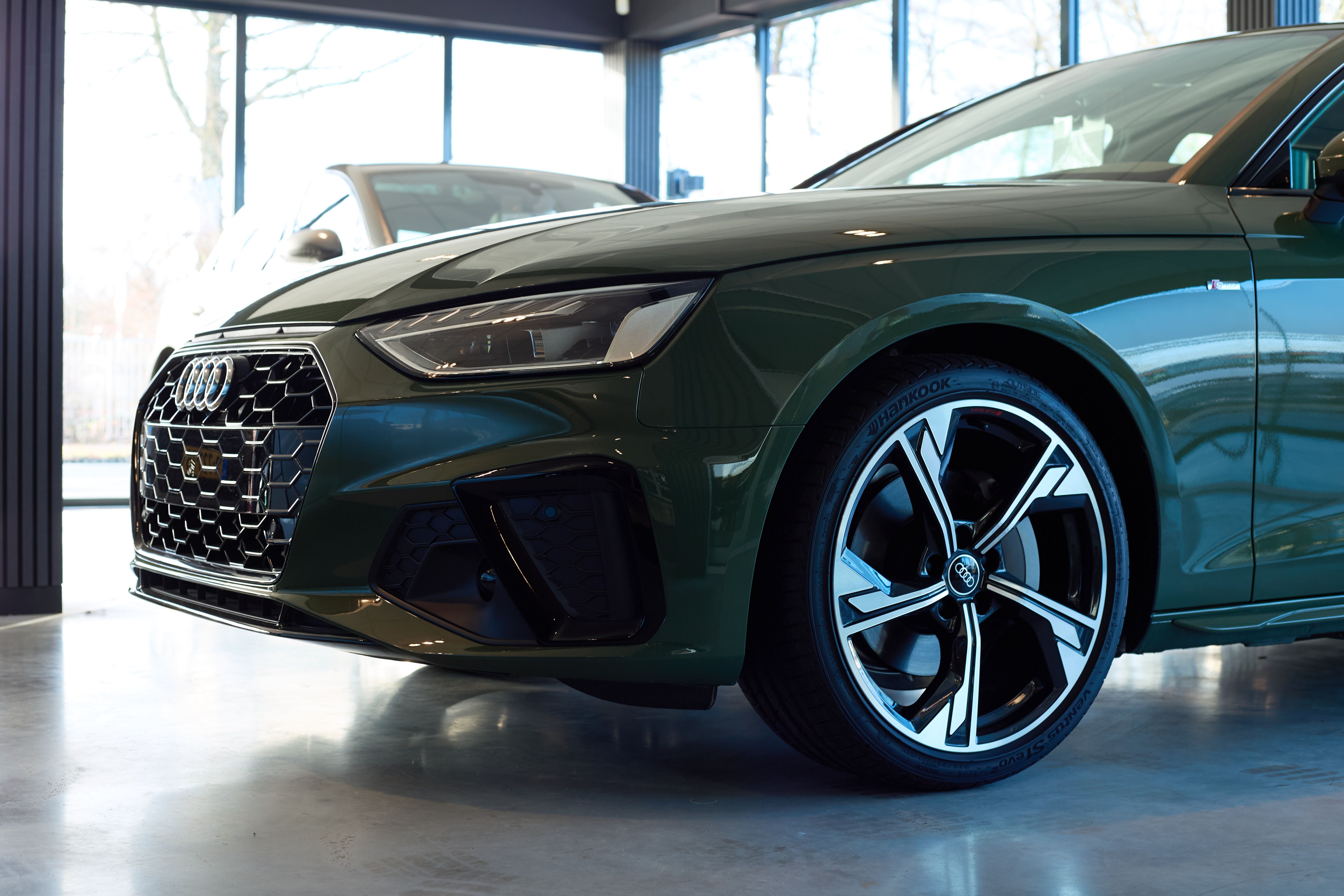 Donkergroene sportieve auto in de showroom van Auto Vreman.