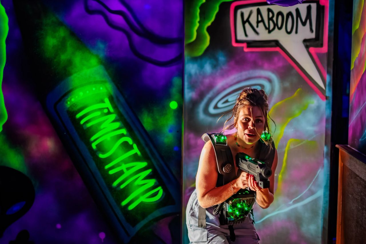 Speelster mikt met een lasergamepistool voor blacklight-graffiti bij Timestamp Arnhem.