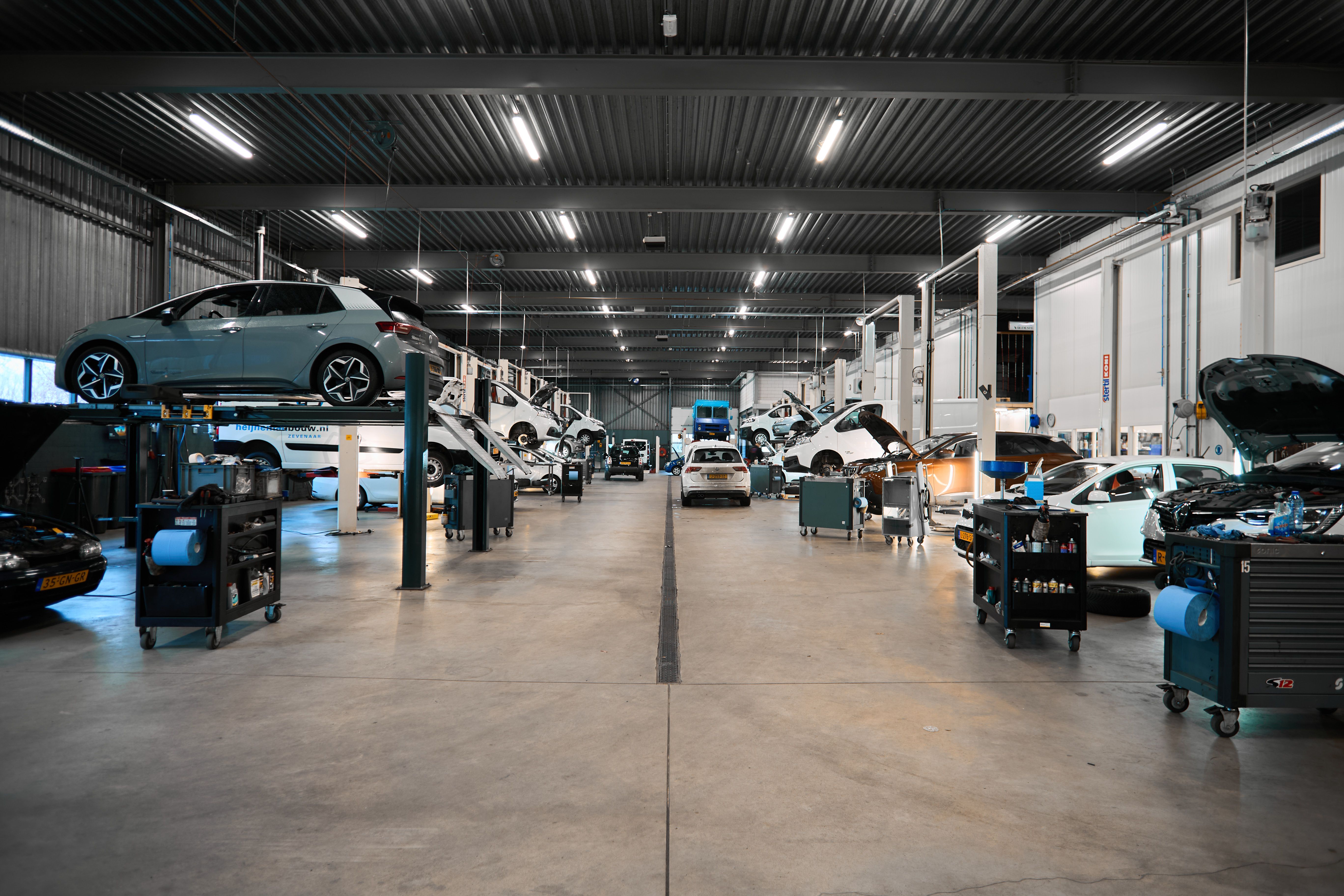 Lange werkplaats met auto's op hefbruggen bij Auto Vreman.