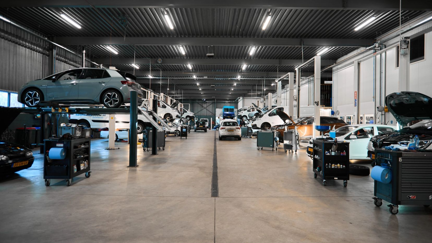 Lange werkplaats met auto's op hefbruggen bij Auto Vreman.