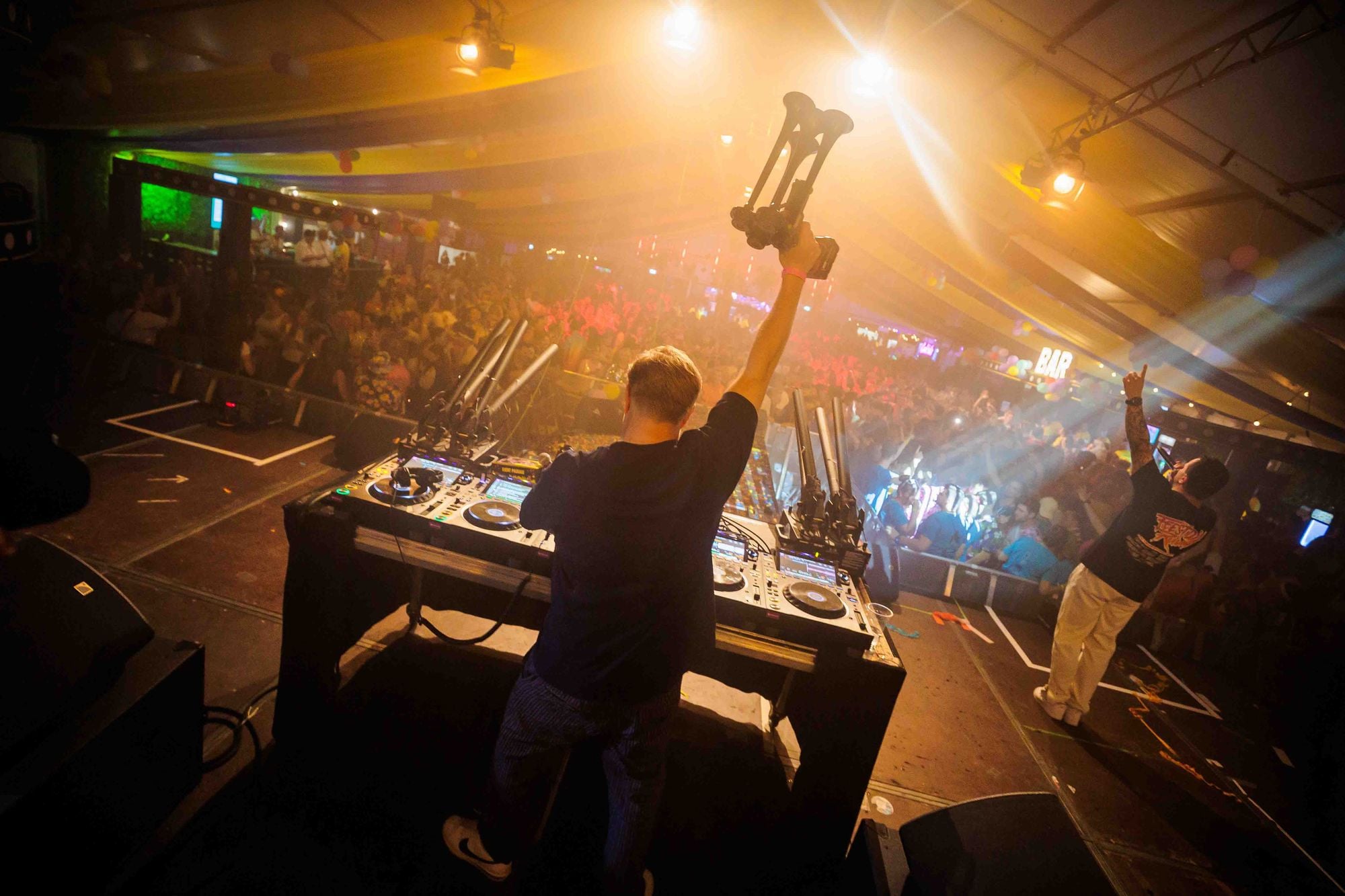 DJ met opgeheven armen achter de draaitafel in warm licht tijdens het Dorpsfeest in Wehl, gemaakt door Bold Productions