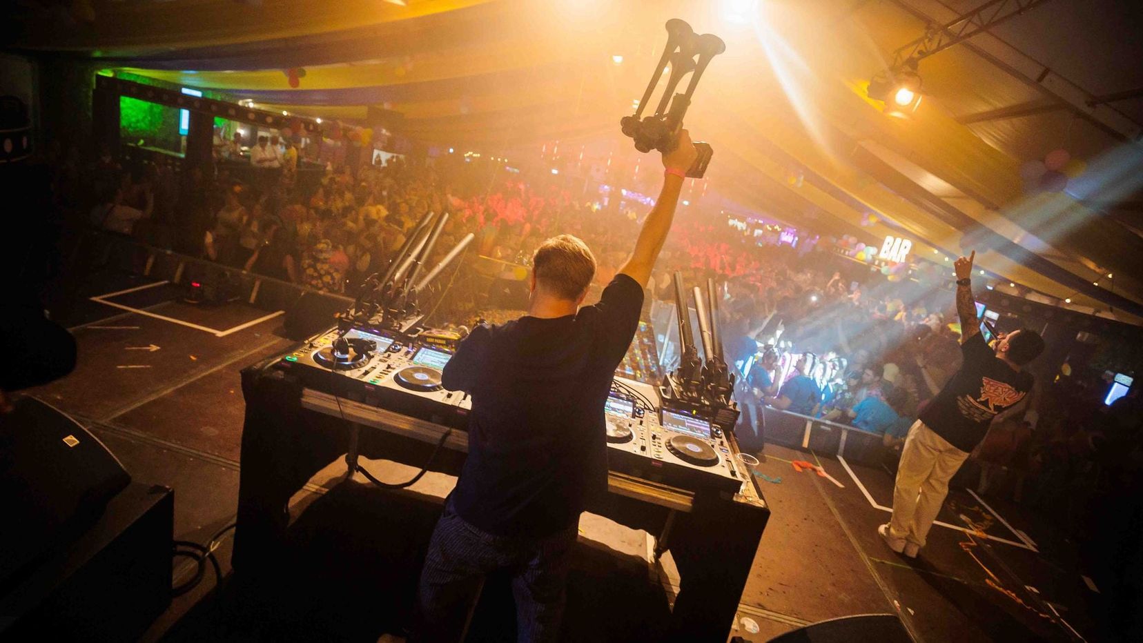 DJ met opgeheven armen achter de draaitafel in warm licht tijdens het Dorpsfeest in Wehl, gemaakt door Bold Productions