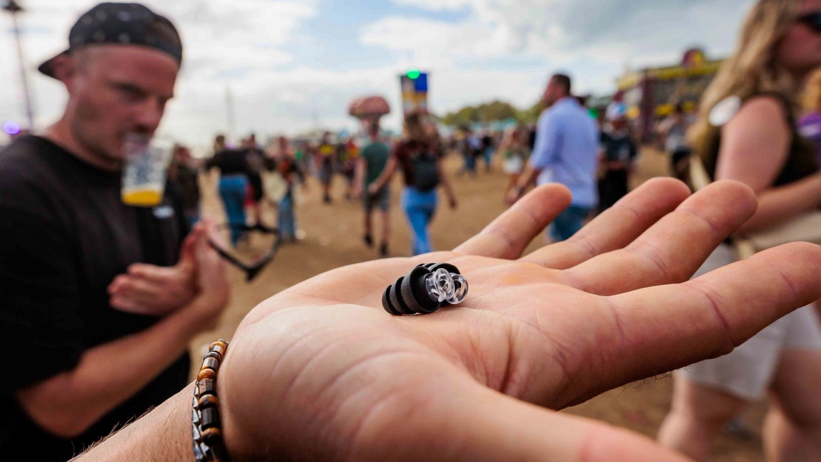 Open hand met een klein oordopje, met festivalgangers onscherp op de achtergrond, gemaakt door Bold Productions