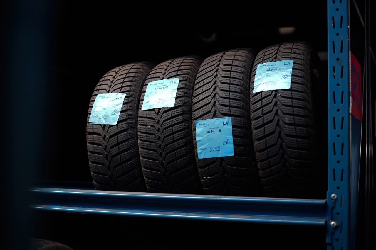 Rij winterbanden met blauwe stickers op een blauw stellingrek.