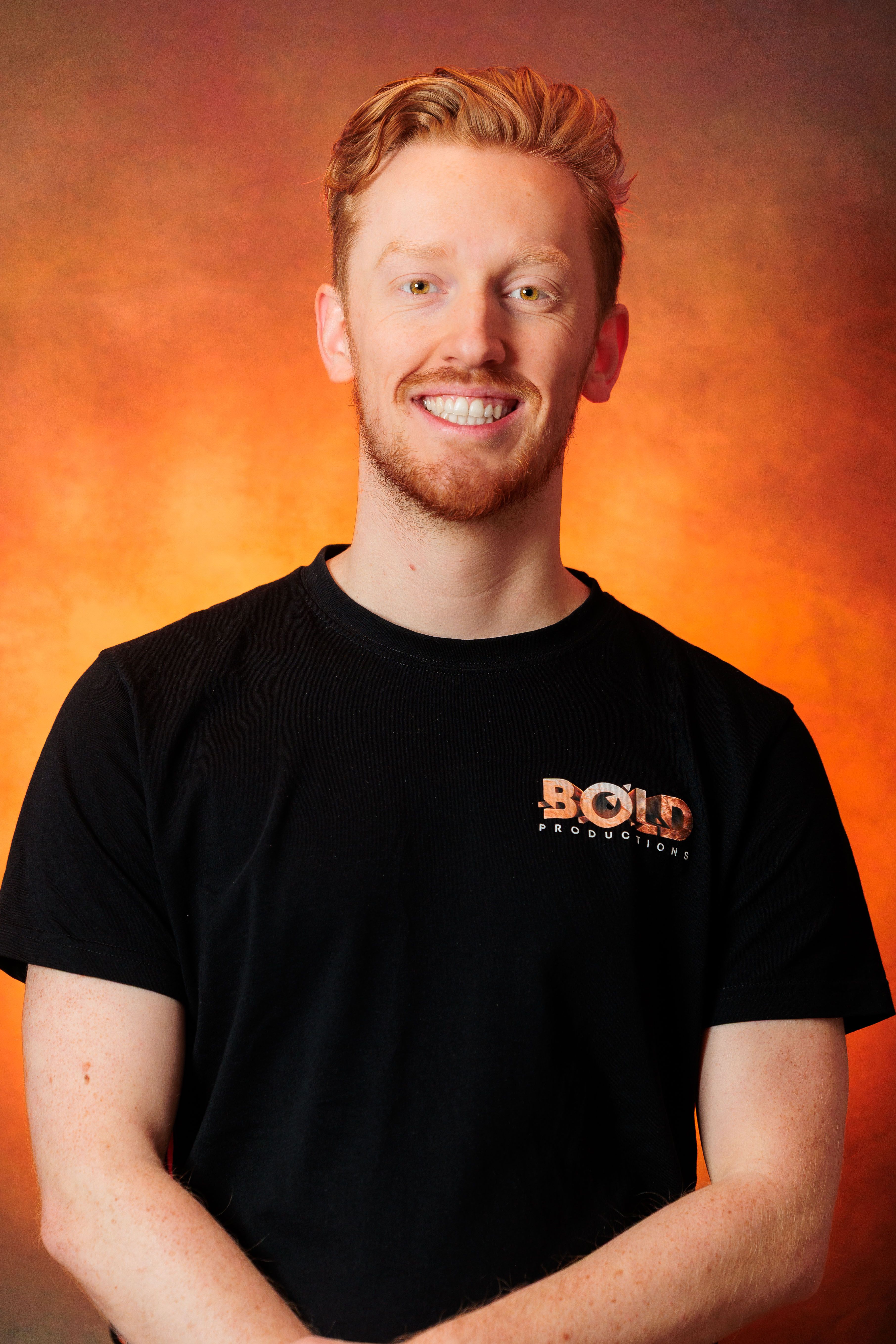 Mike Ampting, eigenaar van Bold Productions, lachend in een zwart Bold-shirt voor een oranje achtergrond.