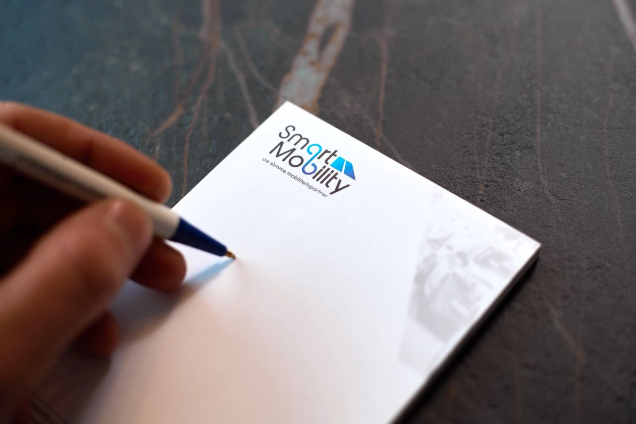 Hand schrijft met een pen op een notitieblok op een donkere tafel.