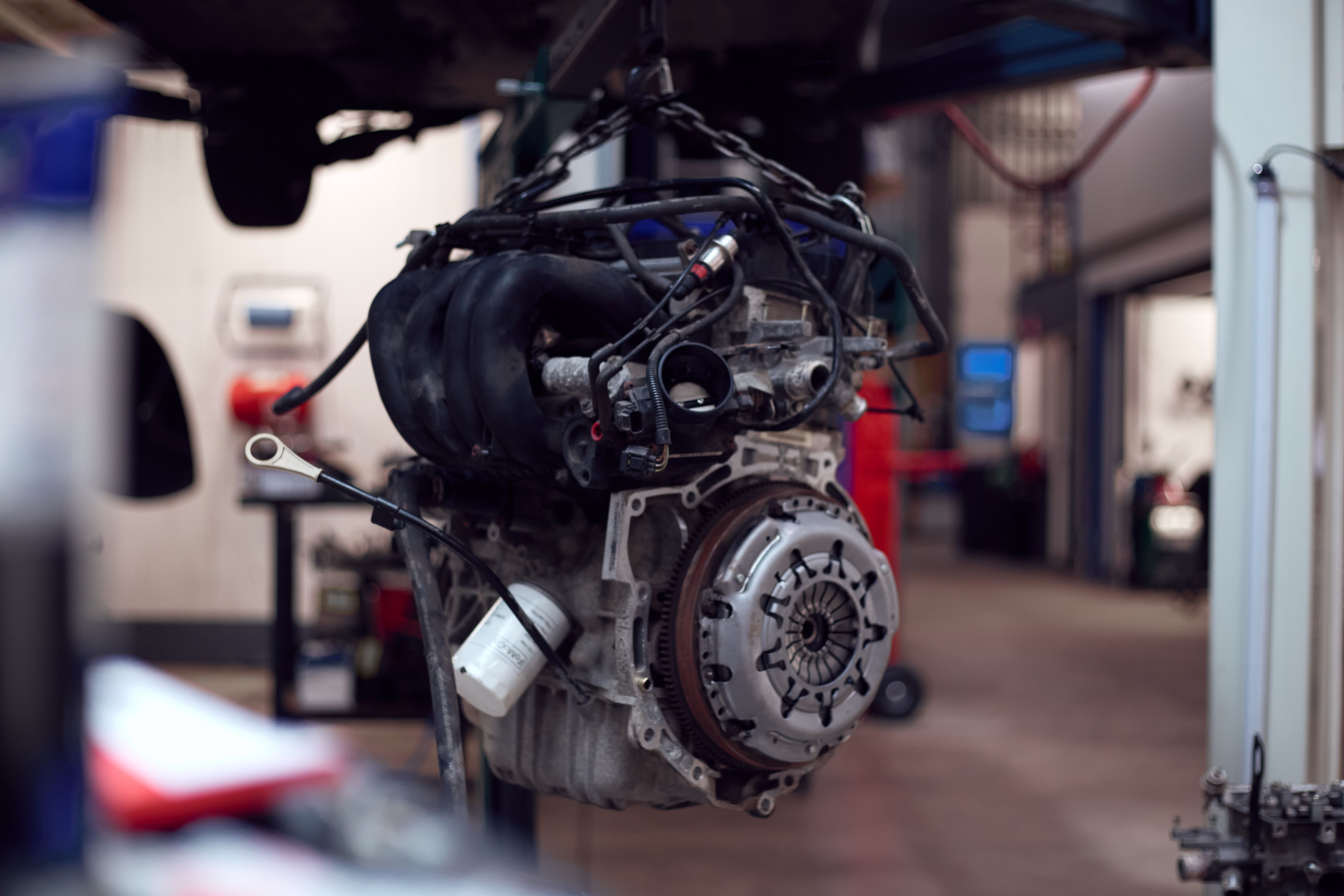 Auto-motor hangt aan de hijsinstallatie in de werkplaats.