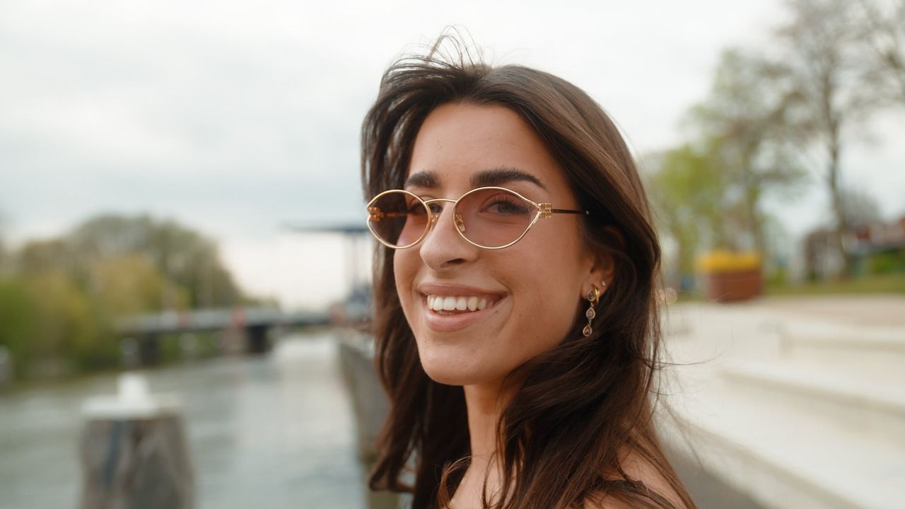 Lachende vrouw met een getinte zonnebril aan het water, gemaakt door Bold Productions