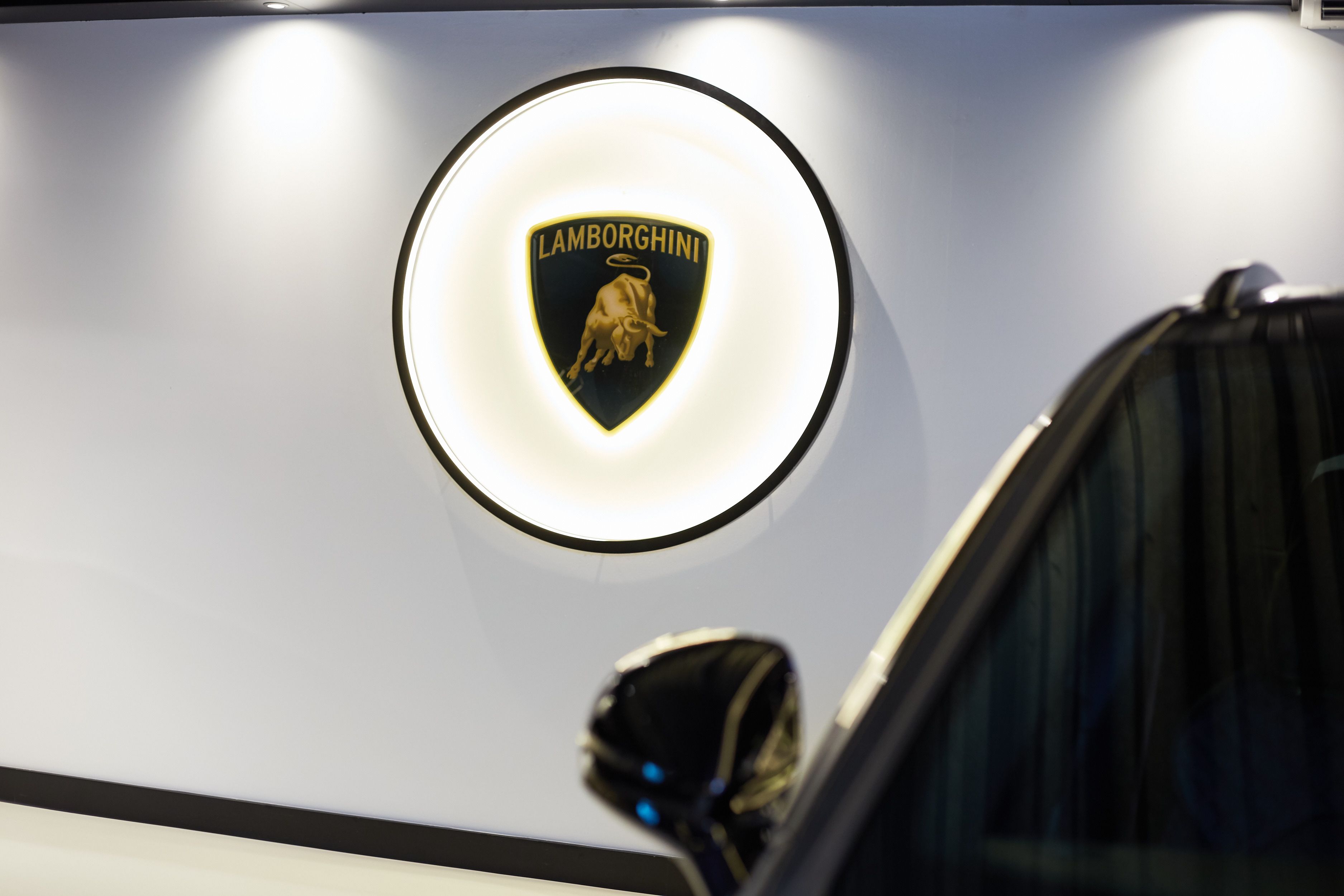Verlicht Lamborghini-logo aan de witte muur van de showroom.