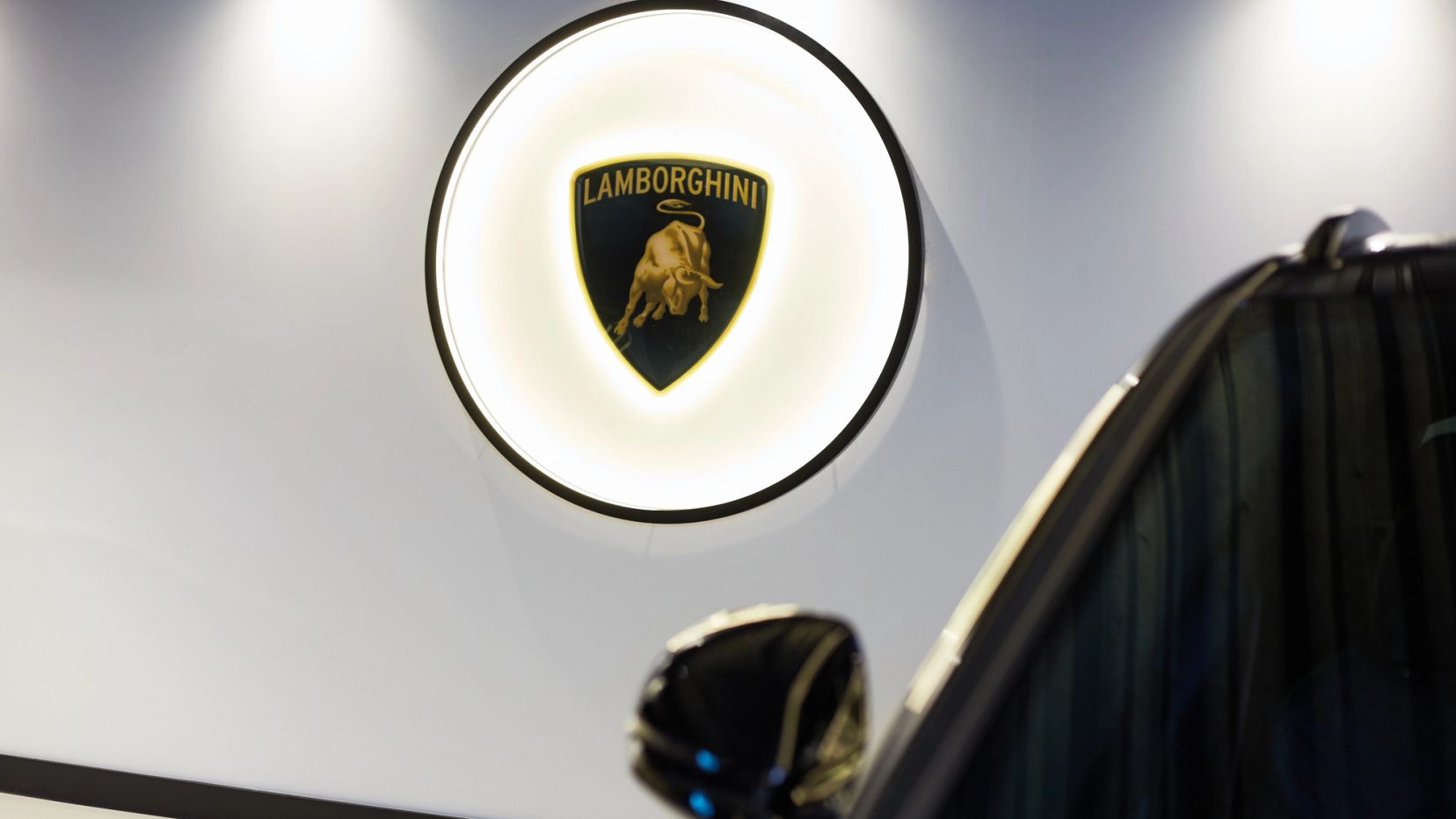 Verlicht Lamborghini-logo aan de witte muur van de showroom.