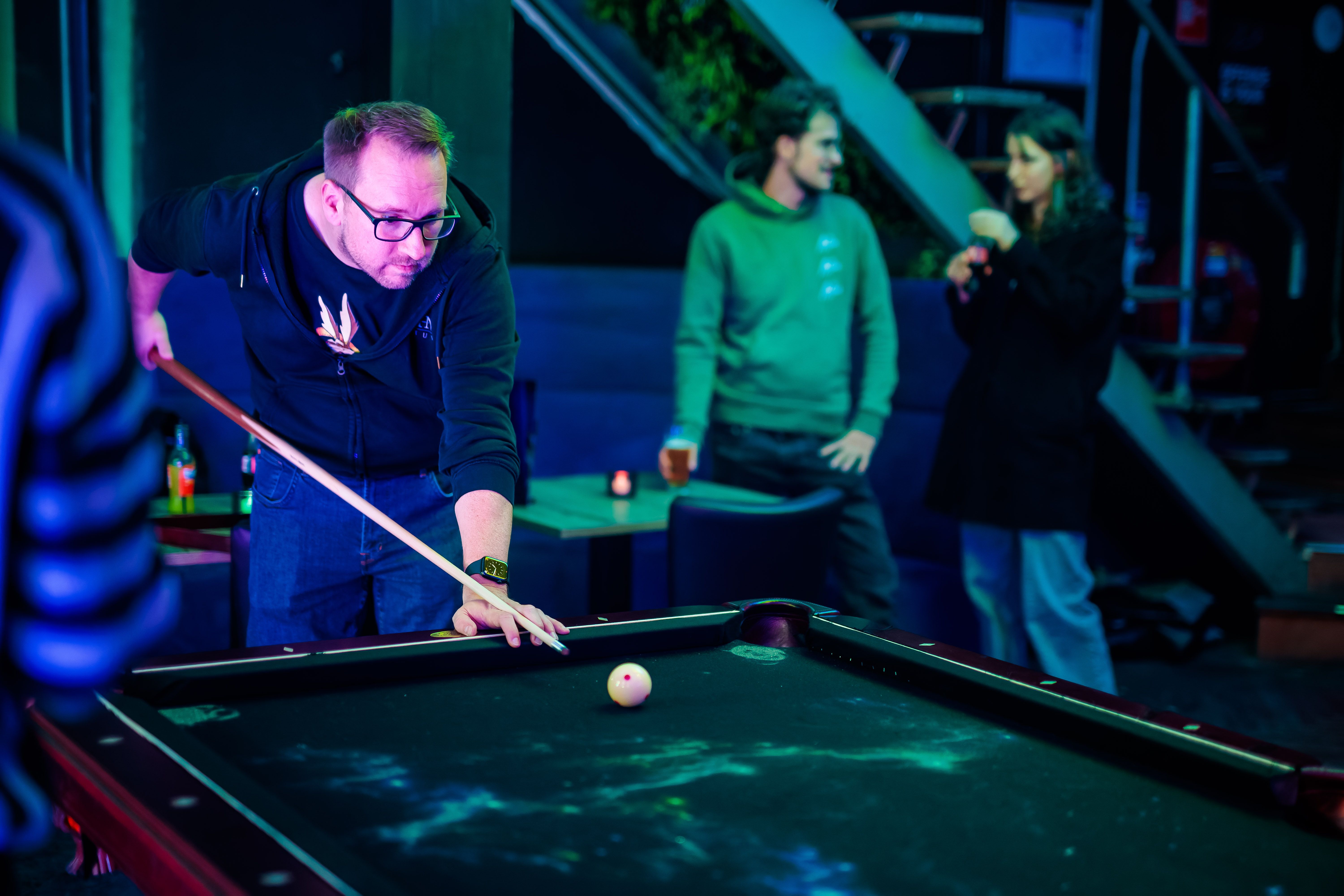 Gast speelt pool in blauw en groen licht bij Timestamp Arnhem.