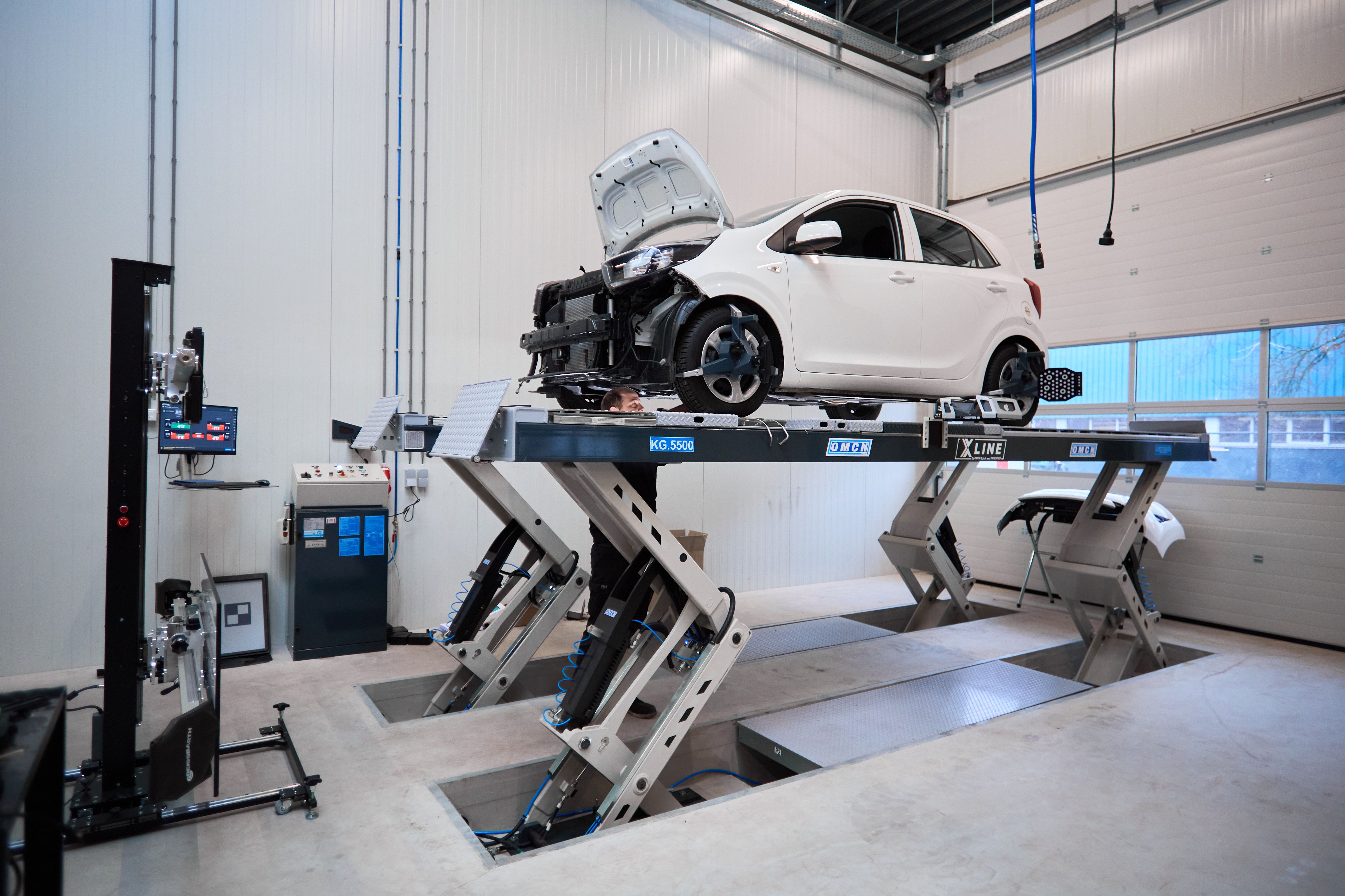 Witte auto op de uitlijnbank in de lichte werkplaats van Auto Vreman.