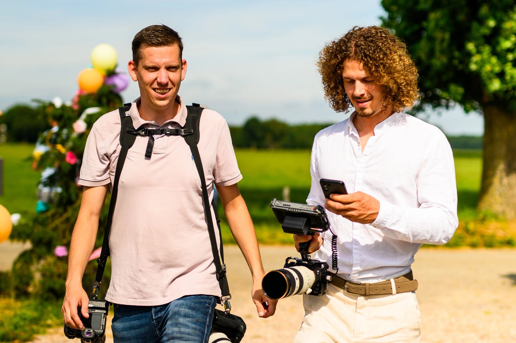 Twee fotografen van Bold Productions lopen met hun camera’s over een festivalterrein.