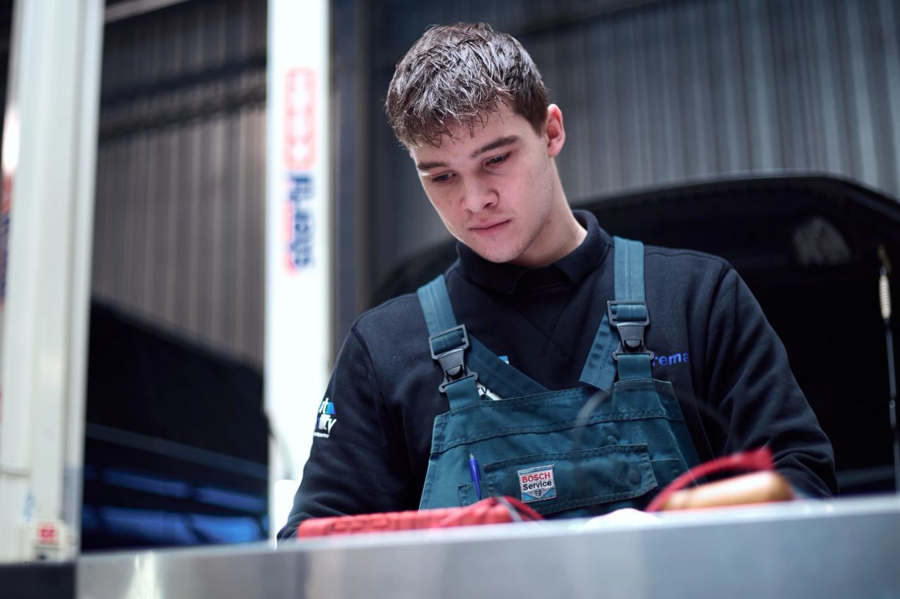 Jonge monteur in overall aan het werk bij Auto Vreman.