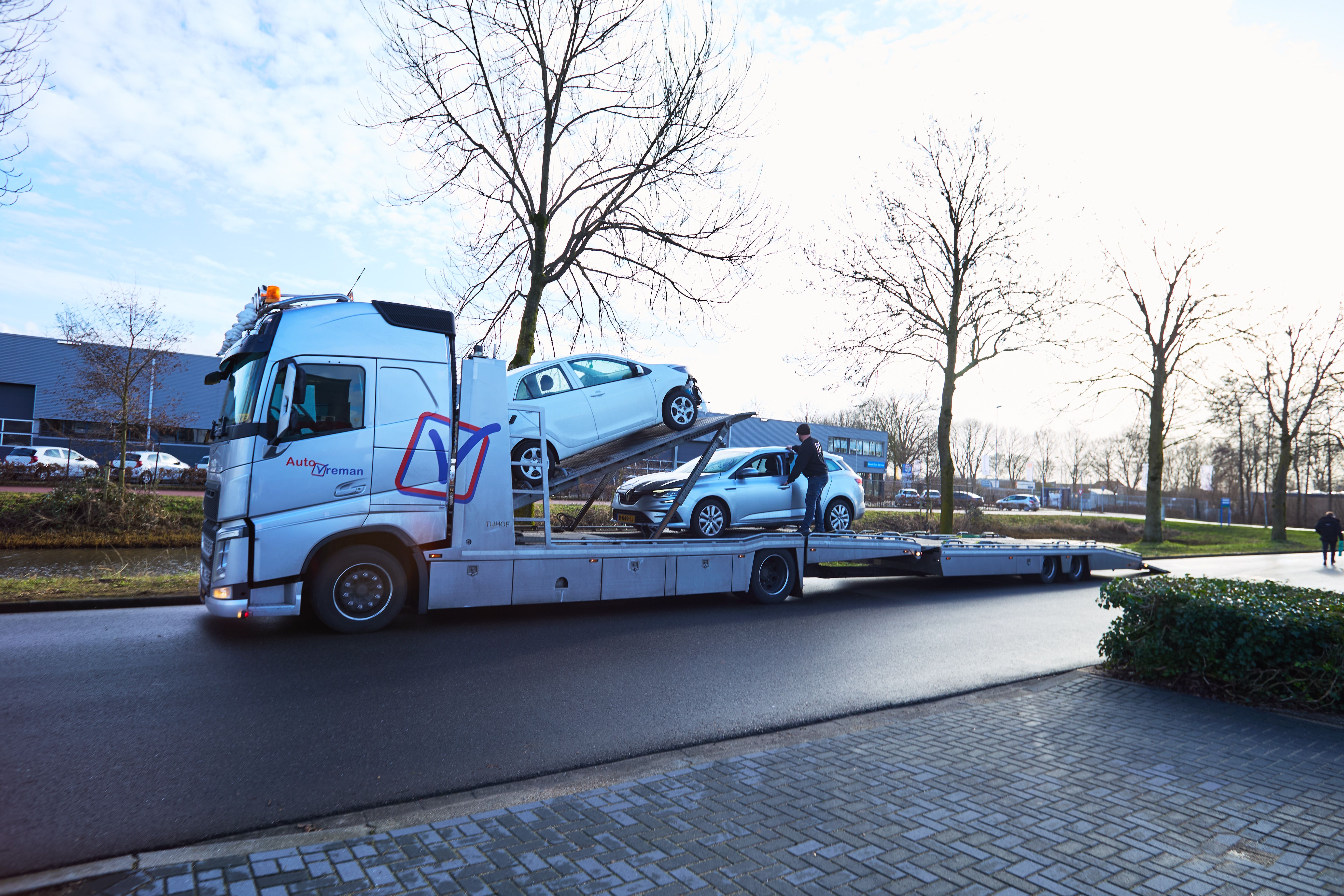 Autotransporter met twee auto's op de oplegger bij Auto Vreman.