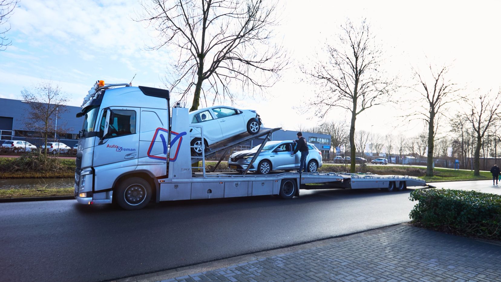 Autotransporter met twee auto's op de oplegger bij Auto Vreman.