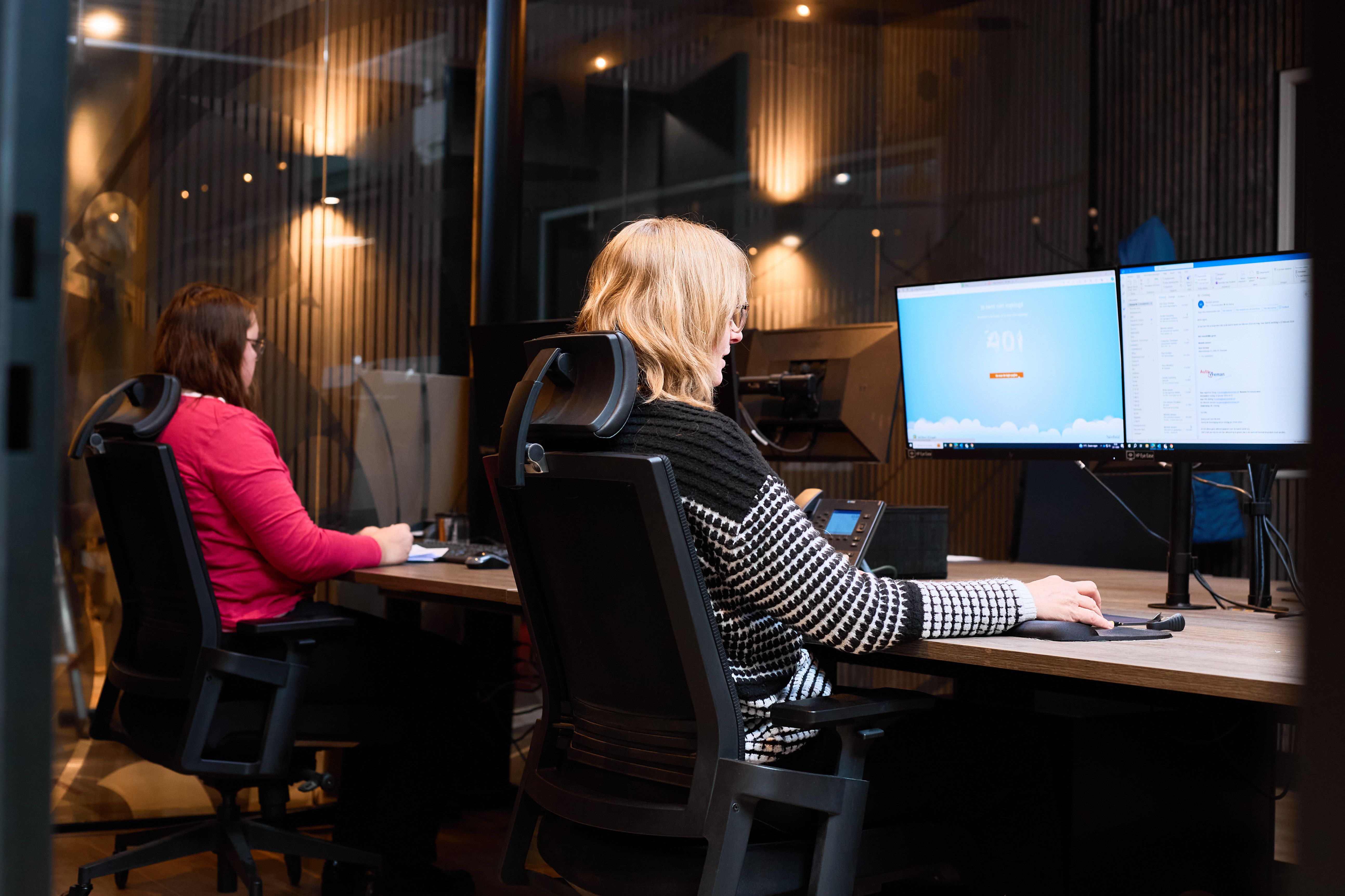 Twee collega's werken achter hun computers op de administratie van Auto Vreman.