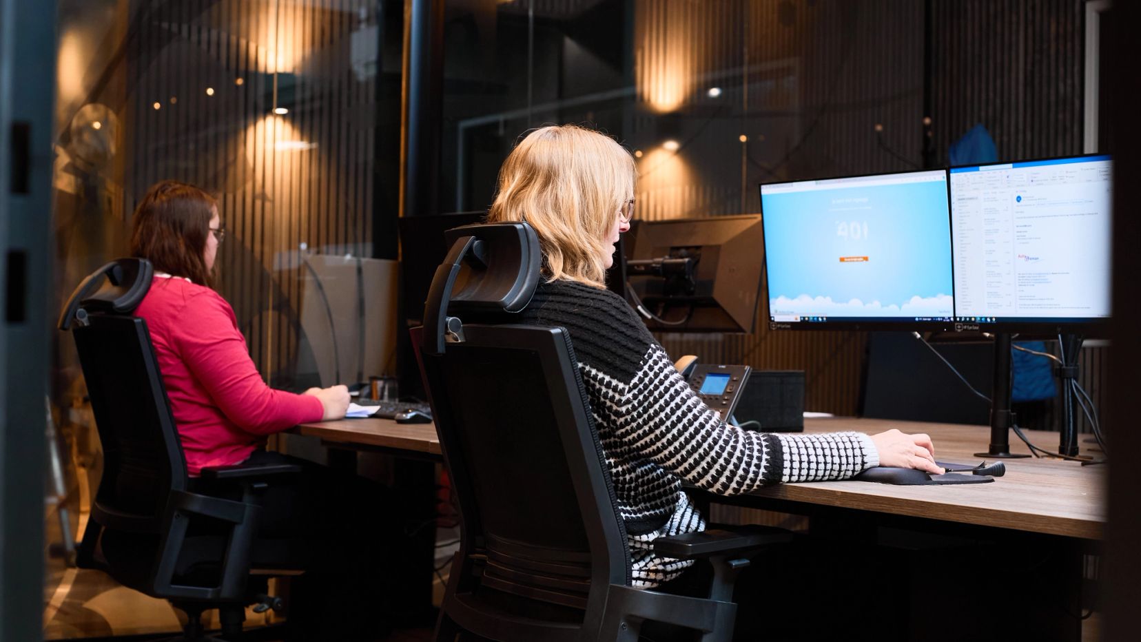 Twee collega's werken achter hun computers op de administratie van Auto Vreman.