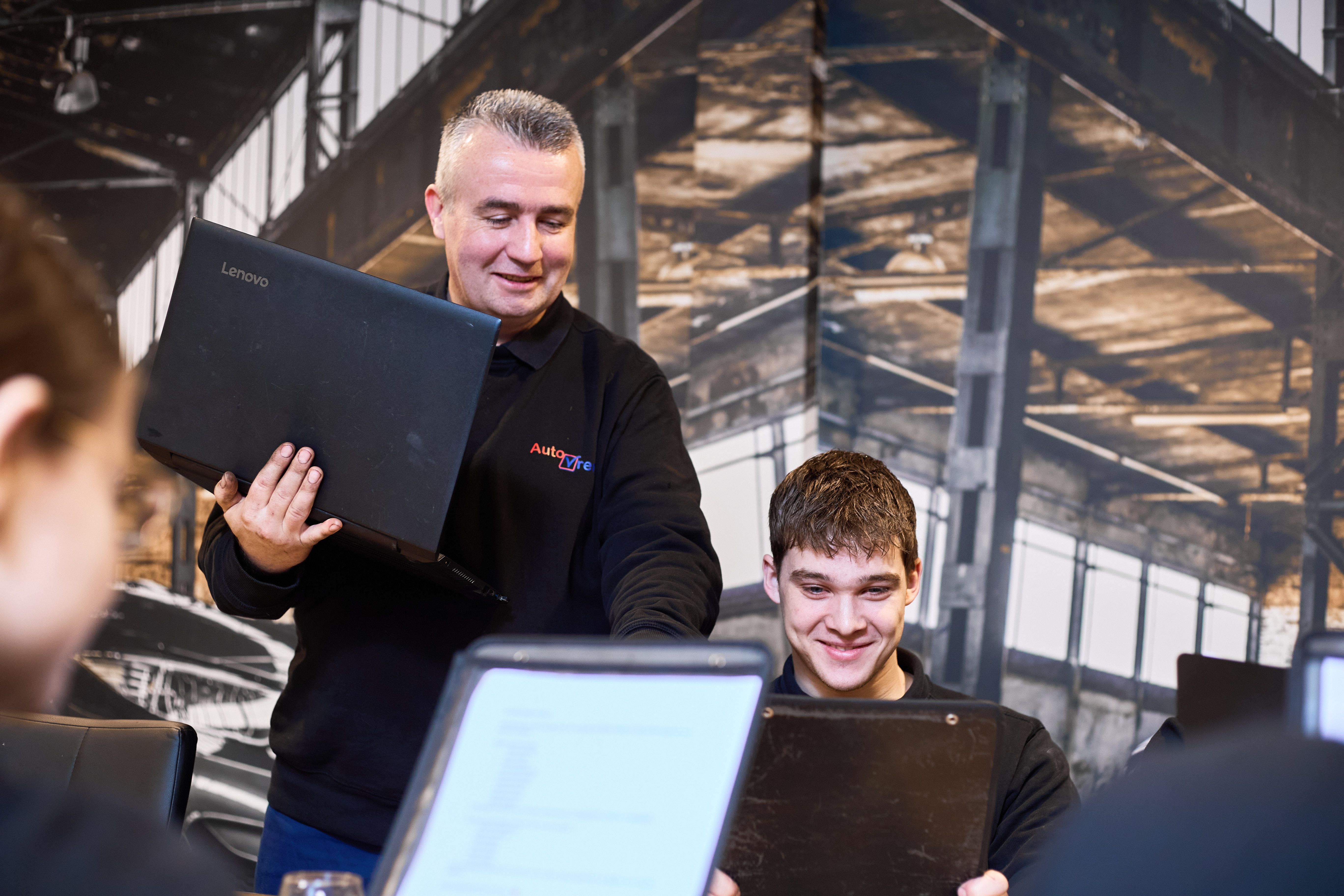 Collega houdt een laptop vast tijdens het overleg met zijn team, gemaakt door Bold Productions