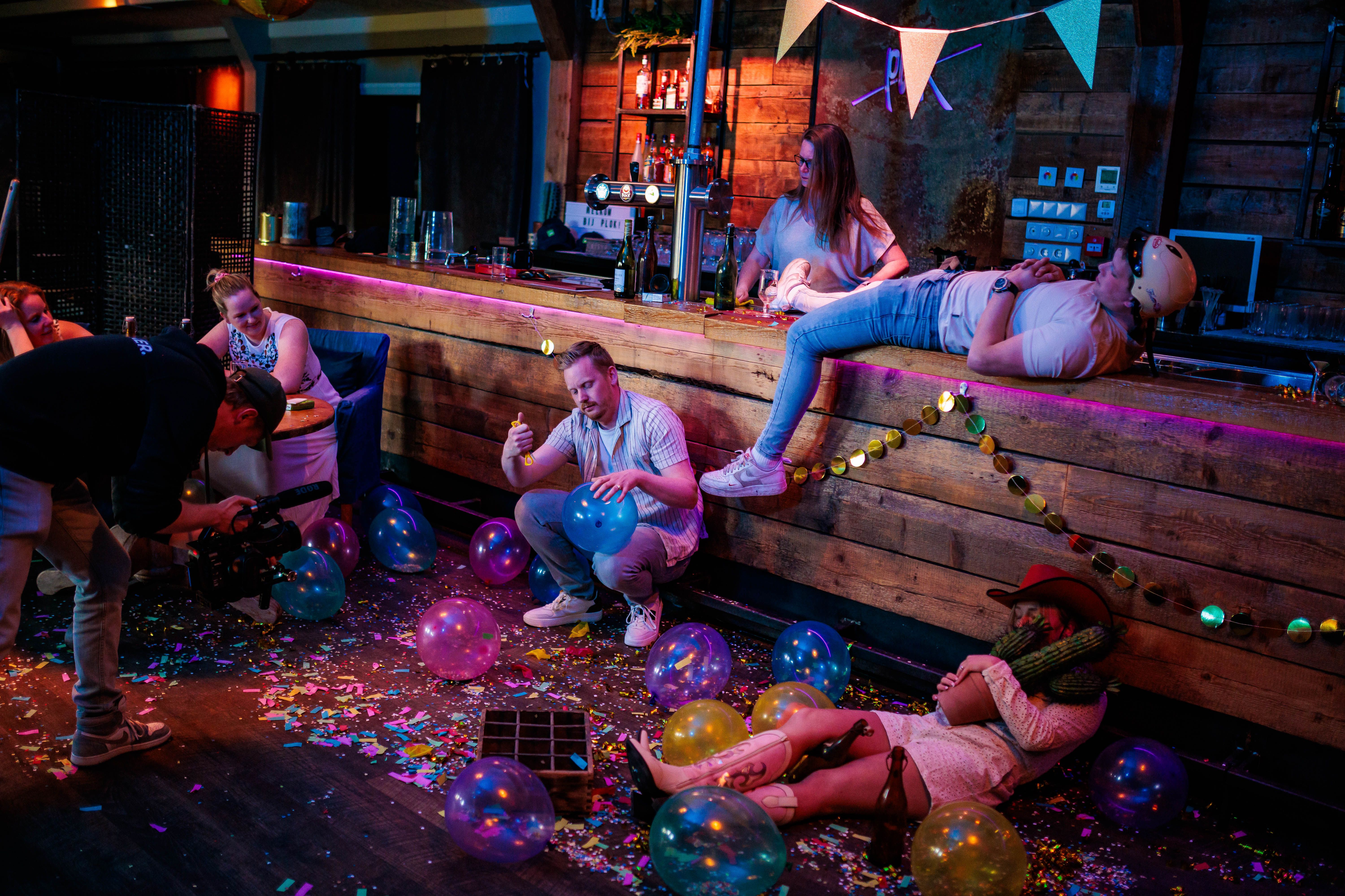 Gasten ontspannen rond een houten bar met slingers en confetti in een rustiek café, gemaakt door Bold Productions