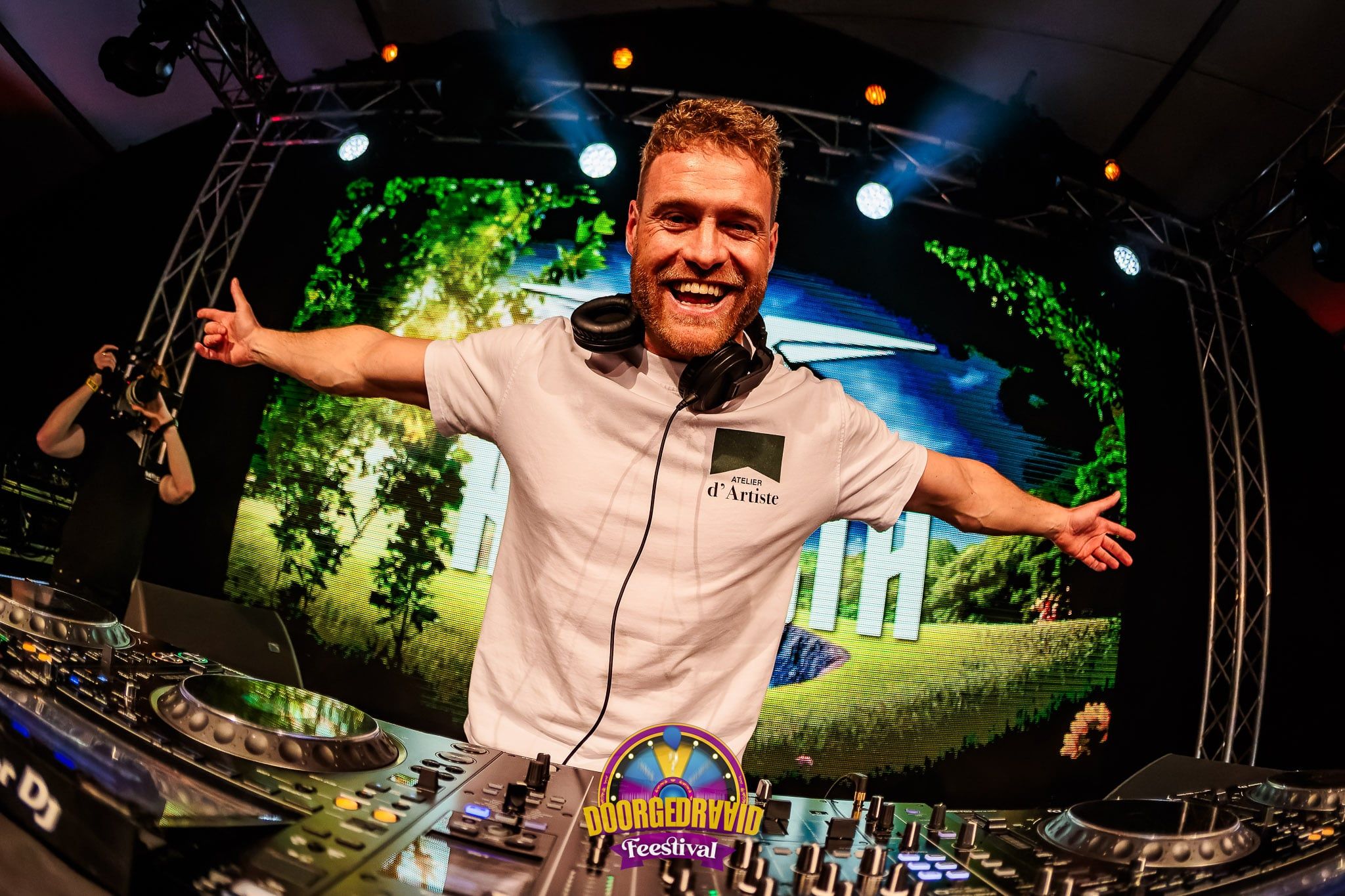 DJ in een wit shirt met uitgestrekte armen en een koptelefoon om zijn nek achter de draaitafel, gemaakt door Bold Productions