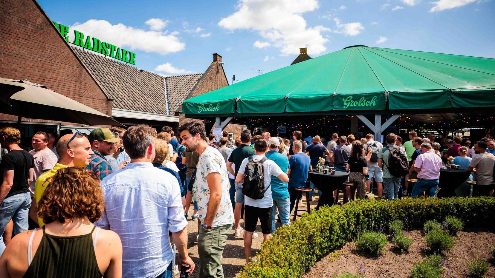 Gasten op een terras met een groene parasol en een kraan op de achtergrond tijdens een bedrijfsfeest, gemaakt door Bold Productions