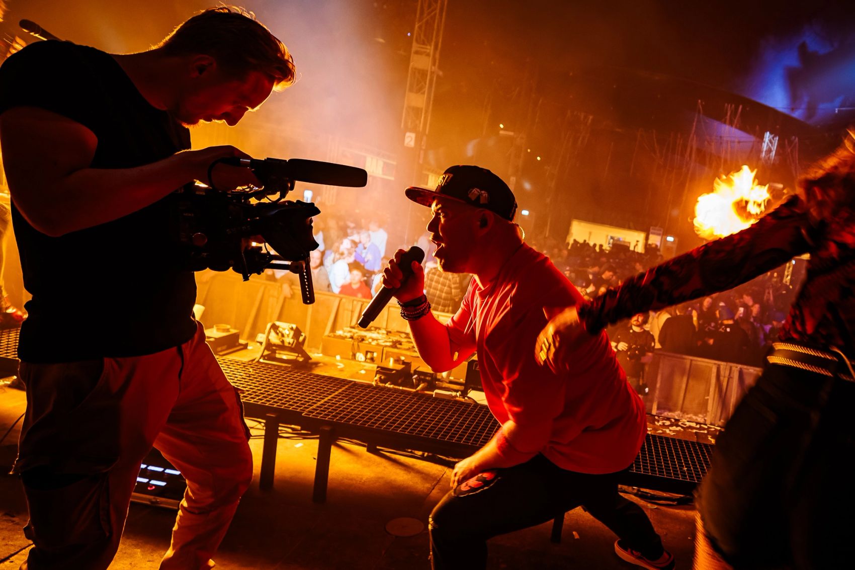 Cameraman van Bold Productions filmt een artiest met een microfoon in oranje licht, gemaakt door Bold Productions