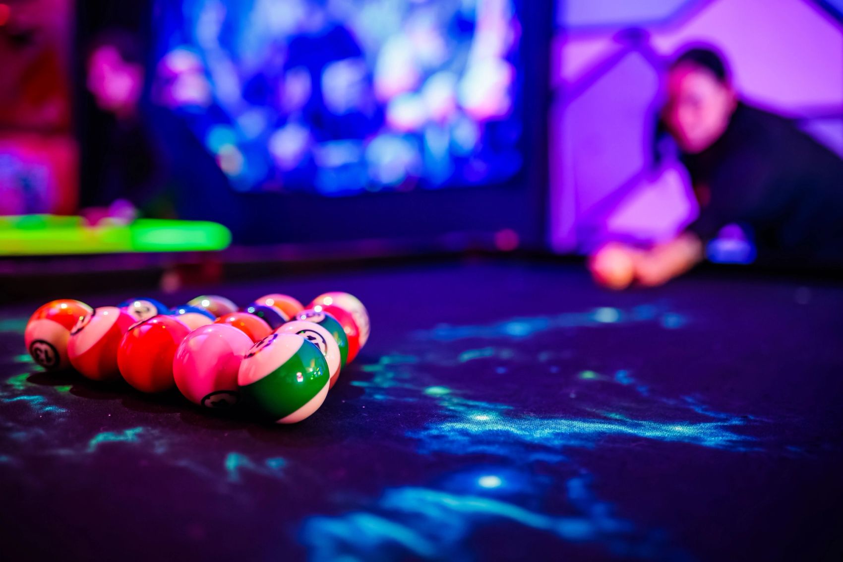Poolballen op een lichtgevend biljart in blauw licht met een speler op de achtergrond, gemaakt door Bold Productions