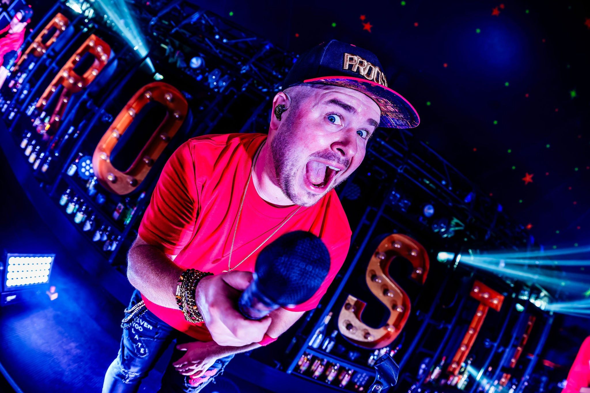 Zanger in een rood shirt met microfoon voor de lichtgevende letters van PROOST!, gemaakt door Bold Productions