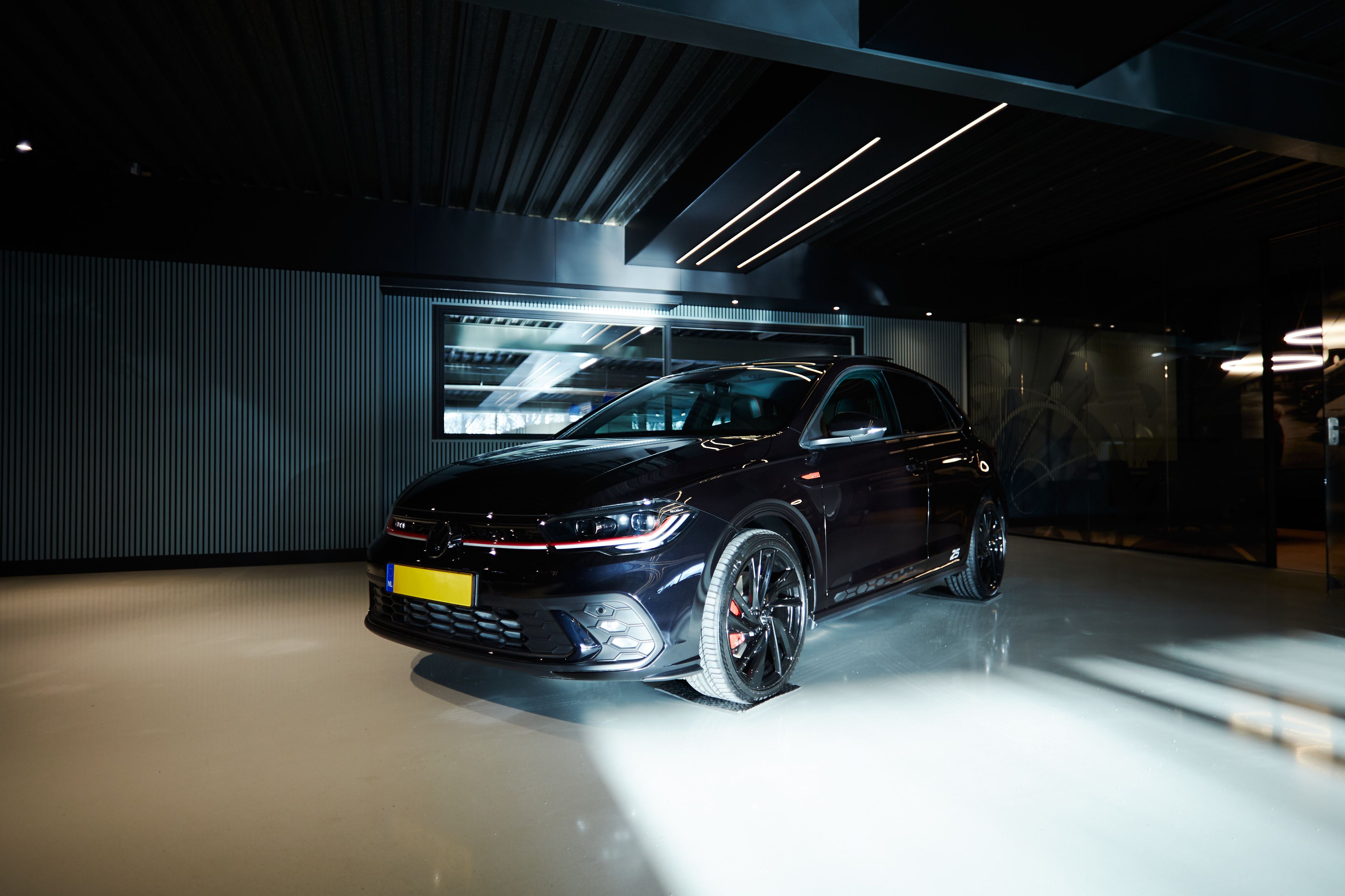 Donkere sportieve auto in een spotlight in de showroom van Auto Vreman.