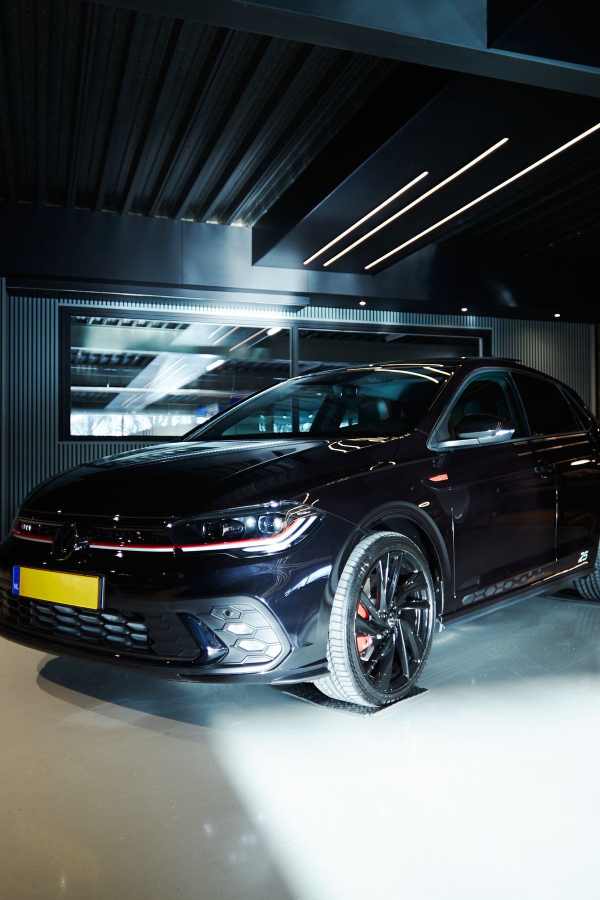 Donkere sportieve auto in een spotlight in de showroom van Auto Vreman.
