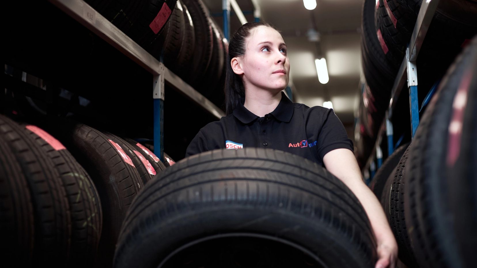 Monteur draagt een band door het bandenmagazijn van Auto Vreman.