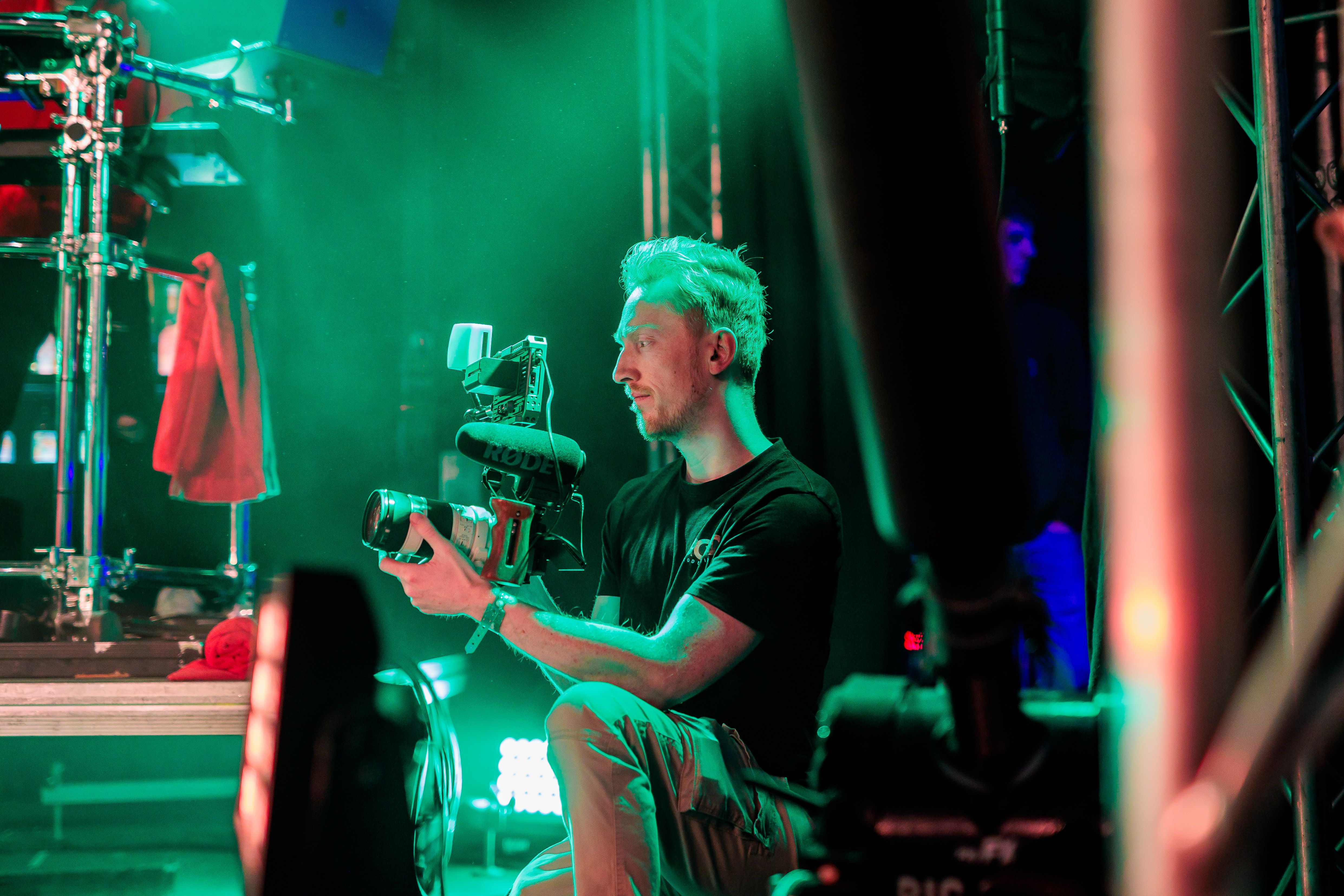 Cameraman van Bold Productions achter zijn camera op een rig in groen podiumlicht, gemaakt door Bold Productions