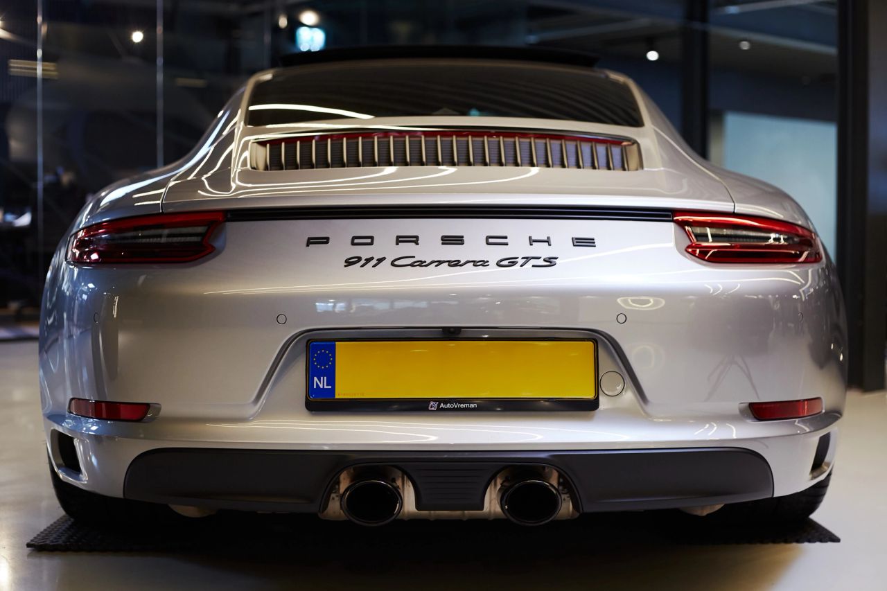 Zilverkleurige Porsche 911 Carrera GTS van achteren in de showroom van Auto Vreman.