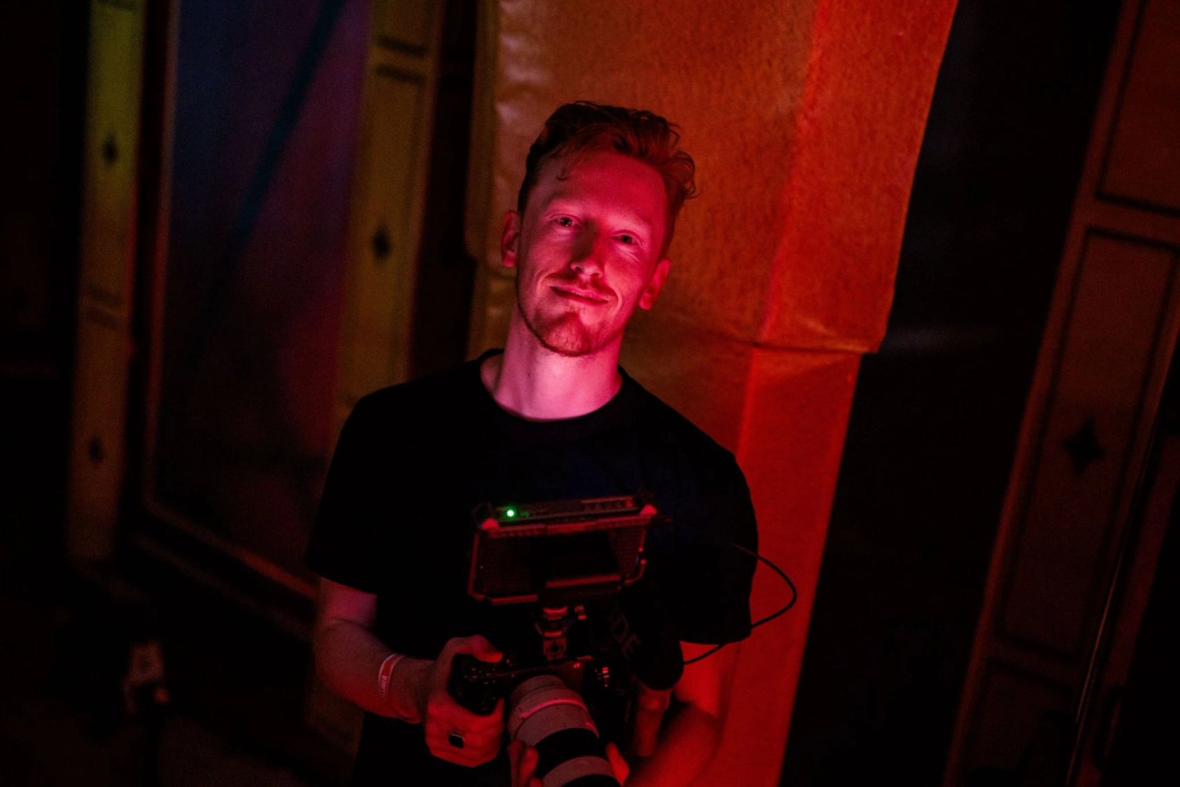 Crewlid van Bold Productions met een camera in een donkere ruimte met oranje licht, gemaakt door Bold Productions