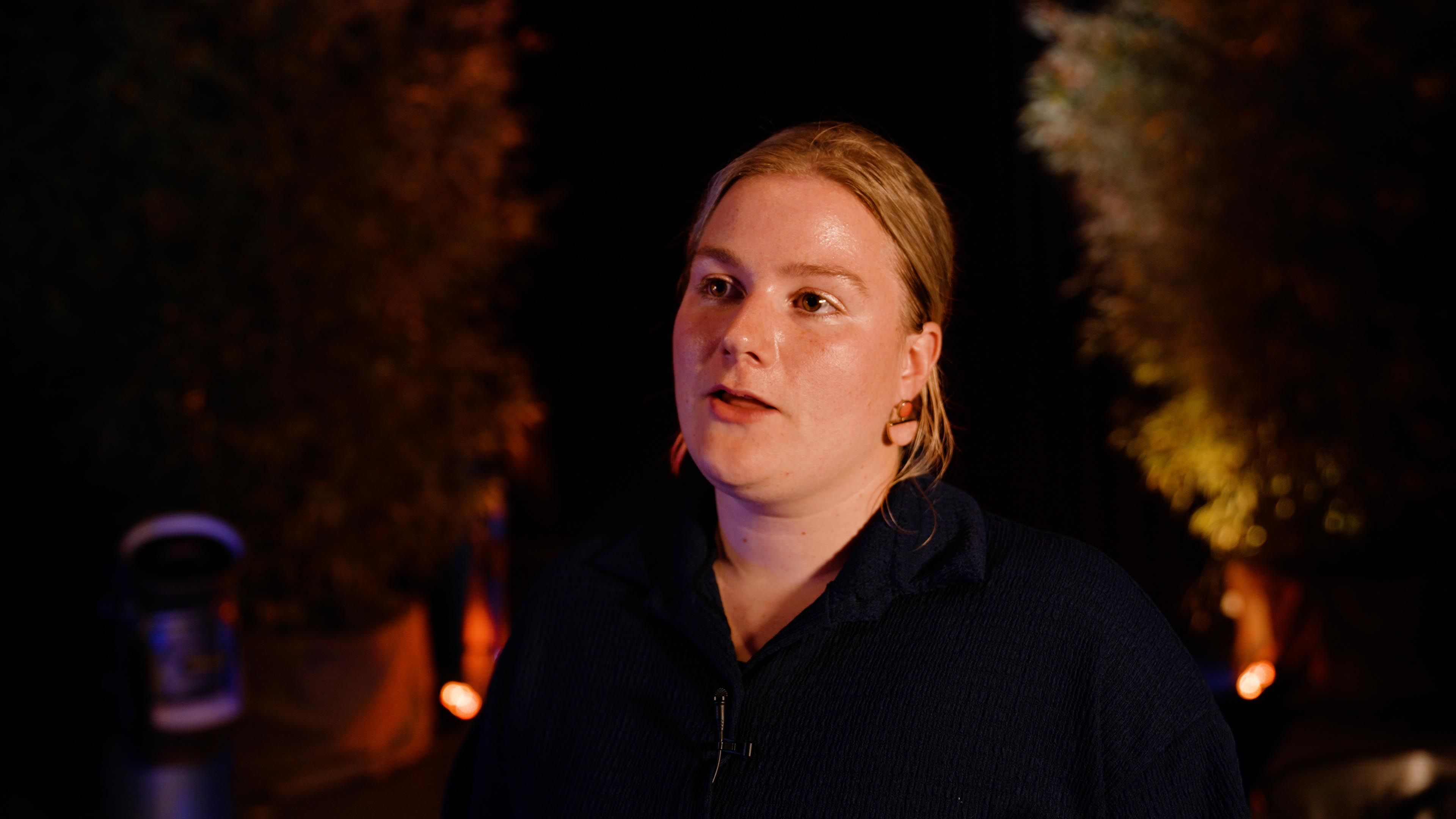 Portret van Manon Diks in het donker met warm licht op de achtergrond